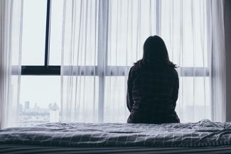 silhouette of a woman sitting in a bed in front of a window