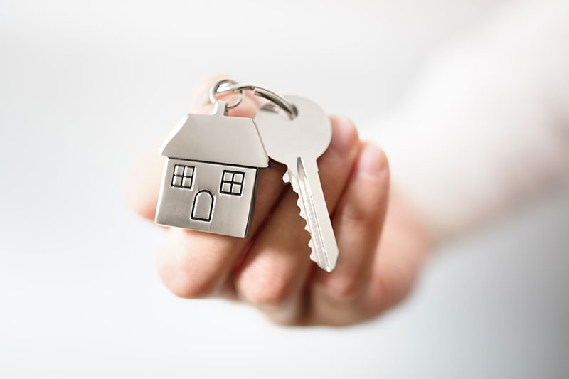 someone holding a keyring in a shape of a house