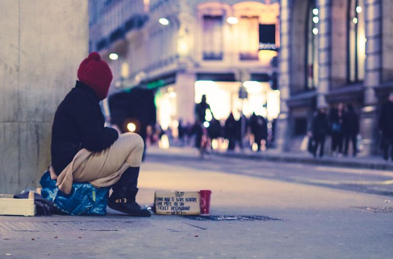 homeless man sitting on the pavement
